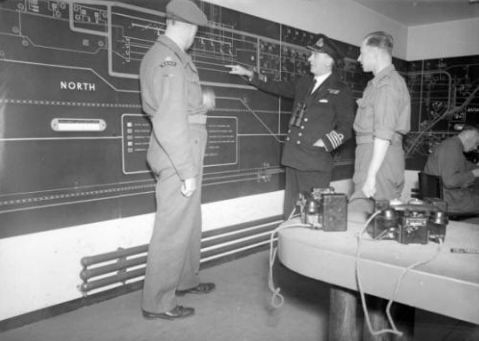 In the main control room at Dungeness. Captain J.F. Hutchings explaining the workings of the control panel which monitored the amount of fuel passing through each pipe line to France.